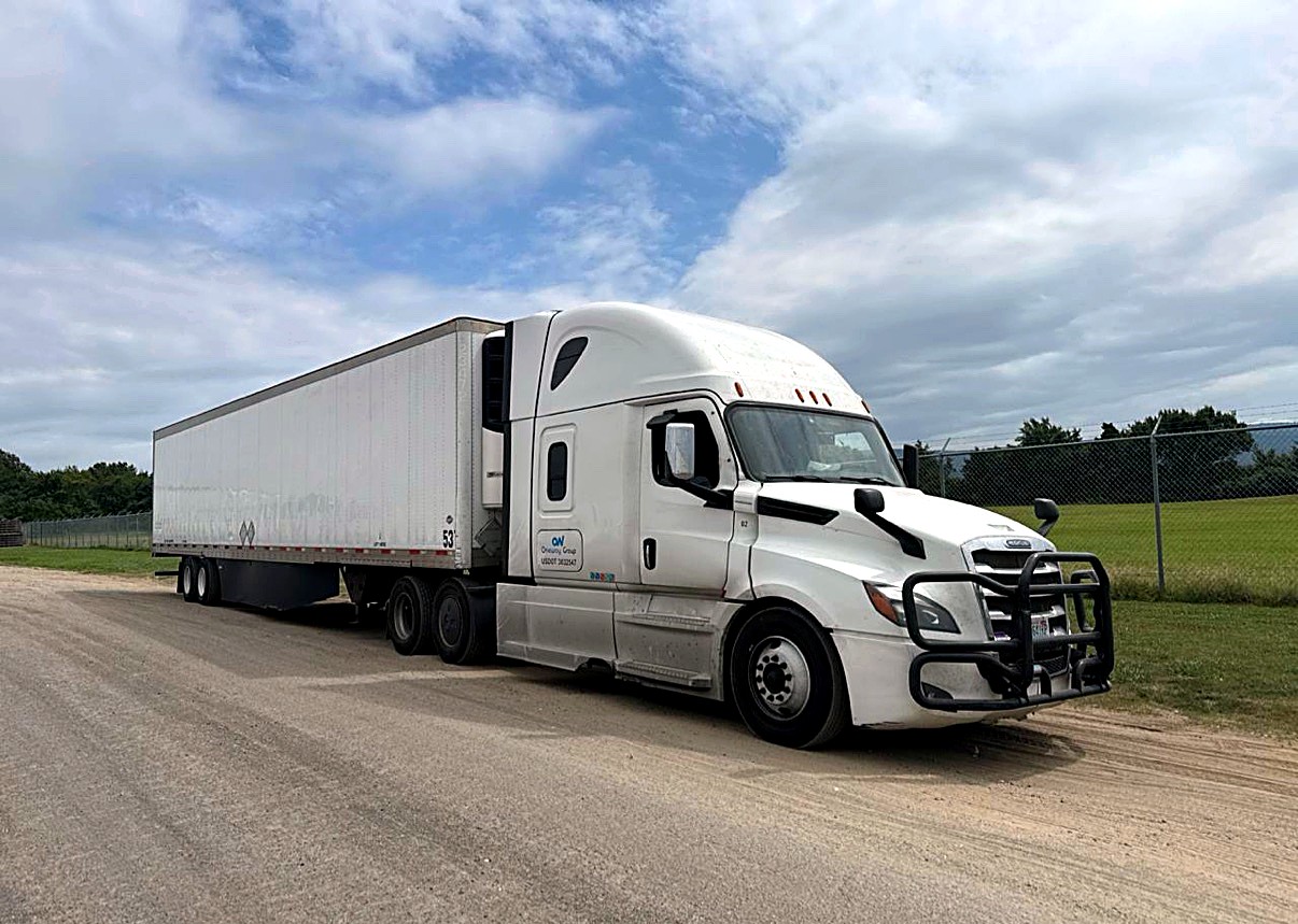 White Oneway Group Freightliner Cascadia pulling a 53-foot trailer on a rural road